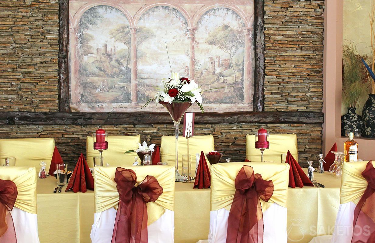 Kokardy z organzy na krzesłach oraz wazon i świeczniki na weselnym stole