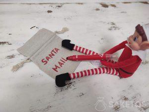 Elf podpisujący woreczek "Santa mail" na liściki od Świętego Mikołaja