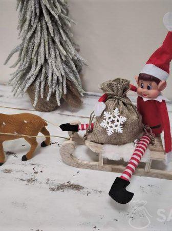 Naughty elf wiozący na saniach worek prezentów