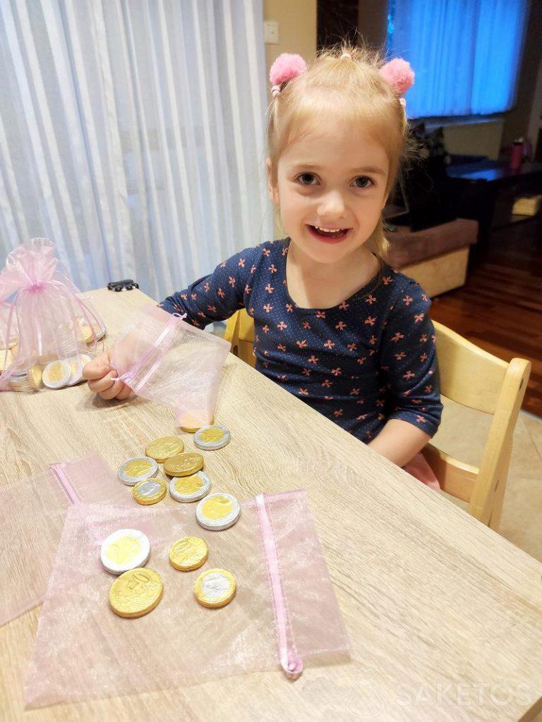 Dziewczynka napełnia woreczki z organzy czekoladowymi monetami