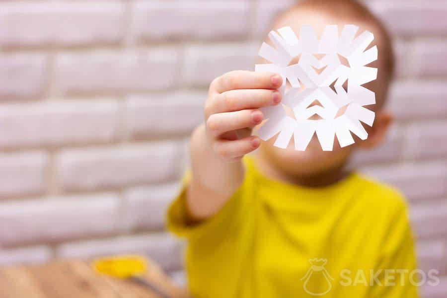 Dziecko wycinające śnieżynkę z papieru