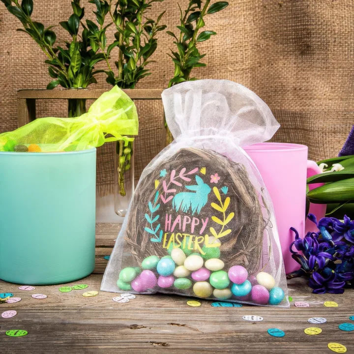 Woreczek z organzy z kolorowym nadrukiem zająca wypełniony cukierkami w kształcie jajek.