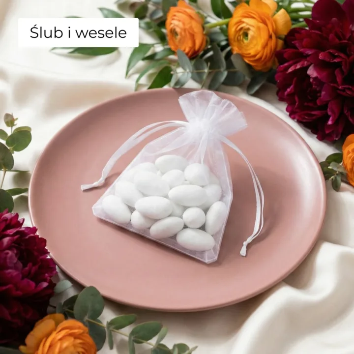 Biały woreczek z organzy z migdałami na talerzu – podziękowanie dla gości.