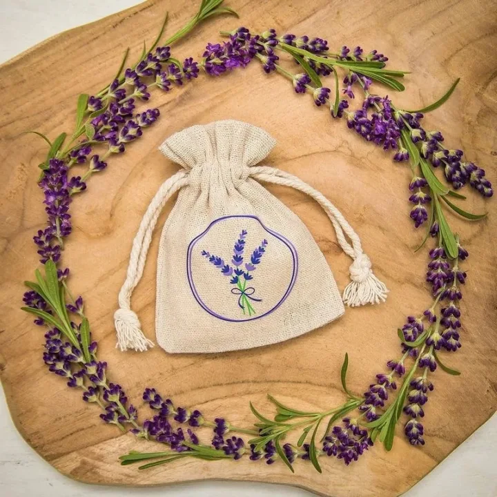 Fioletowy woreczek z organzy wypełniony suszem lawendowym na drewnianym stole.